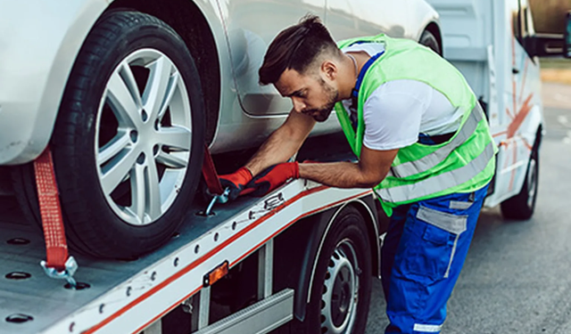 Technician performing emergency roadside assistance and towing services kneeling down to secure wheels using the MobiWork emergency roadside assistance and towing services software solution