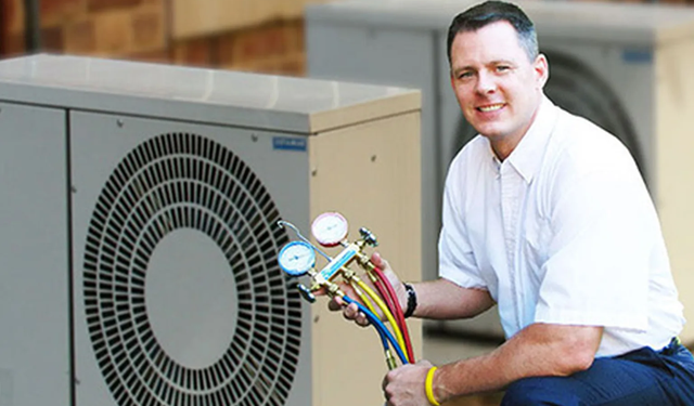 Technician kneeling down near HVAC units on roof using the MobiWork HVAC services software solution