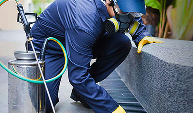 Technician kneeling down outside applying pesticides to the surrounding area using the MobiWork pest control services software solution